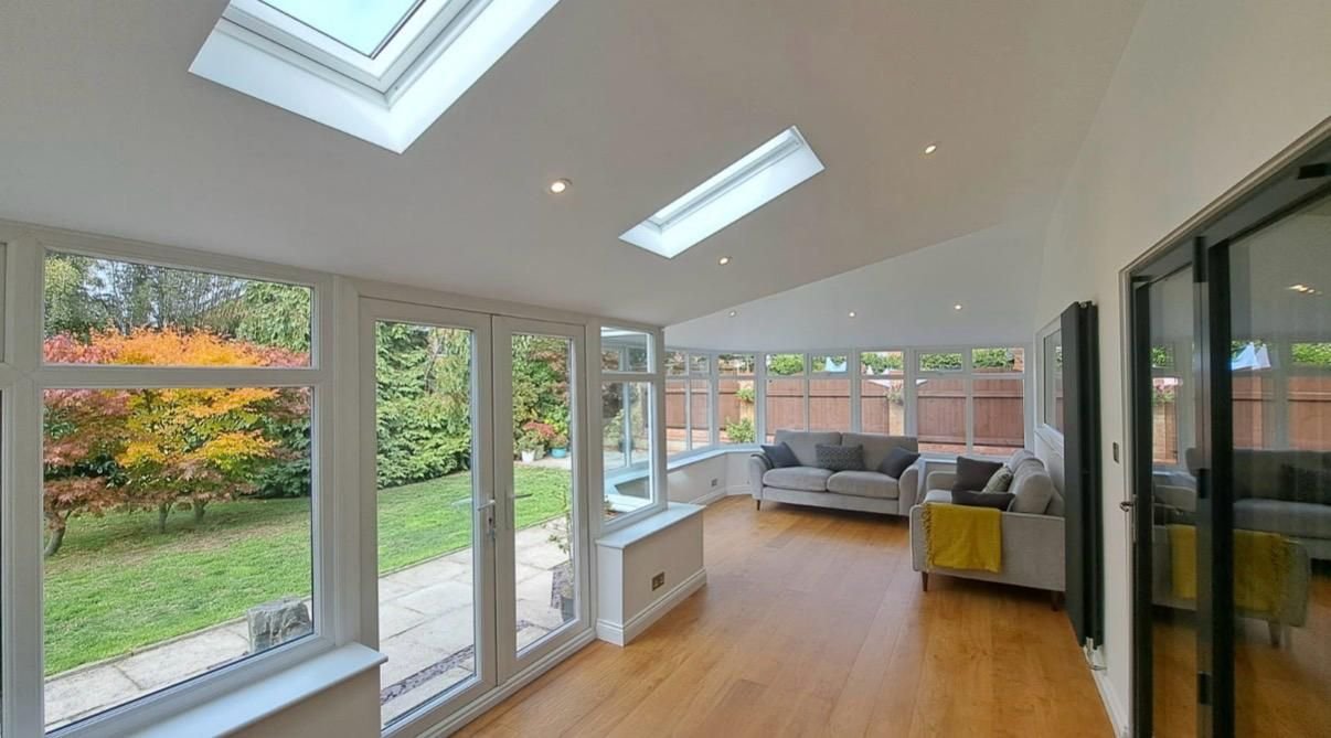 Inside a finished conservatory with roof windows and a plastered ceiling